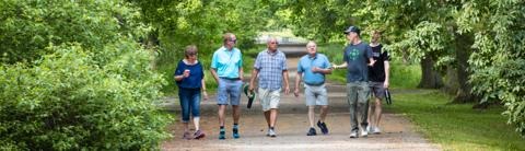 University of Guelph alumni participating in an Arboretum walk during a workshop event on a tree-lined path.