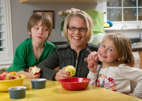Mom with two kids eating apples at table
