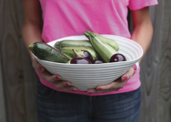 Girl in pink shirt holding a bowl of eggplant
