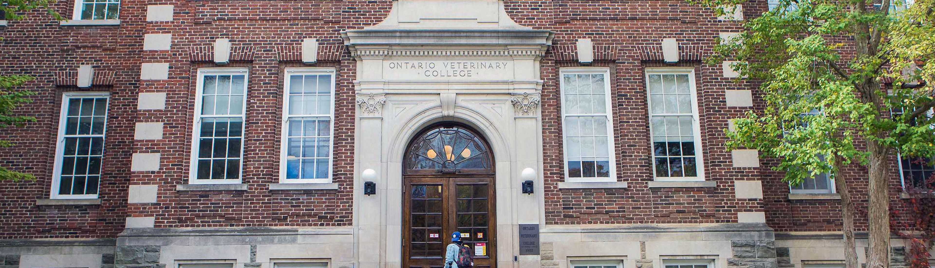 Front entrance of the Ontario Veterinary College building, surrounded by trees in early spring 