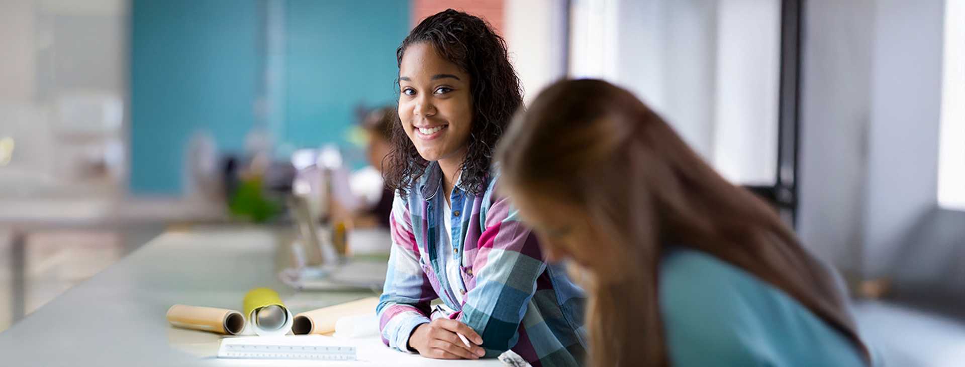 Student sitting at a table smiling 